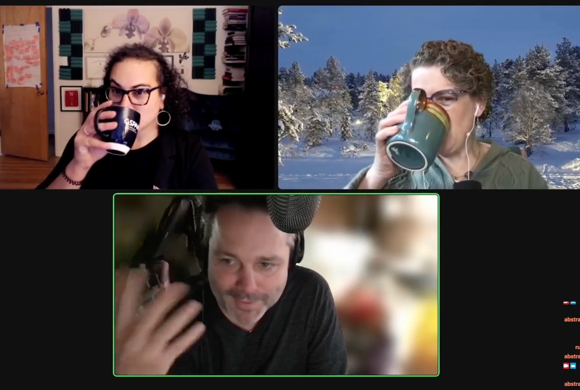 Screenshot of a Zoom meeting with three participants. On the top left is Alex Hanna, an Arab woman with curly black hair. She is wearing hoop earrings, glasses and a black shirt, and his holding a small blue coffee mug up to her mouth. Behind her is a wall covered in art. On the top right is Emily M. Bender, a white woman with curly brown hair. She wears glasses and a gray sweatshirt, and is holding a teal coffee mug up to her mouth. Behind her is an image of snow-covered conifer trees under a night sky. At the bottom is Justin Hendrix, a white man with stubble and short brown hair. He is wearing a black t-shirt and large headphones, and his background has been blurred.