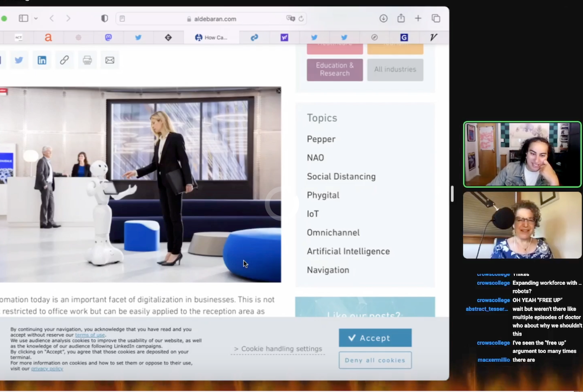 Screenshot of a Zoom meeting with two participants. On the left is a screenshared image that appears to be of a white-floored office lobby with blue, round benches for seating. A blond woman wearing a black business suit and high heels is holding out her right hand to a white-colored humanoid robot that stands at the height of her waist. They appear about to shake hands. On the right are the thumbnails of the participants. On the bottom panel is Emily Bender, a white woman with short-ish curly brown hair. She wears glasses, earrings, and a blue and white top. Behind her is a room with beige walls and a window with closed off-white blinds. On the top panel is Alex Hanna, an Arab woman with black, curly hair to her shoulders. She is wearing a gray button-up shirt over a white shirt. Behind her is a room with multiple pieces of art on the walls.