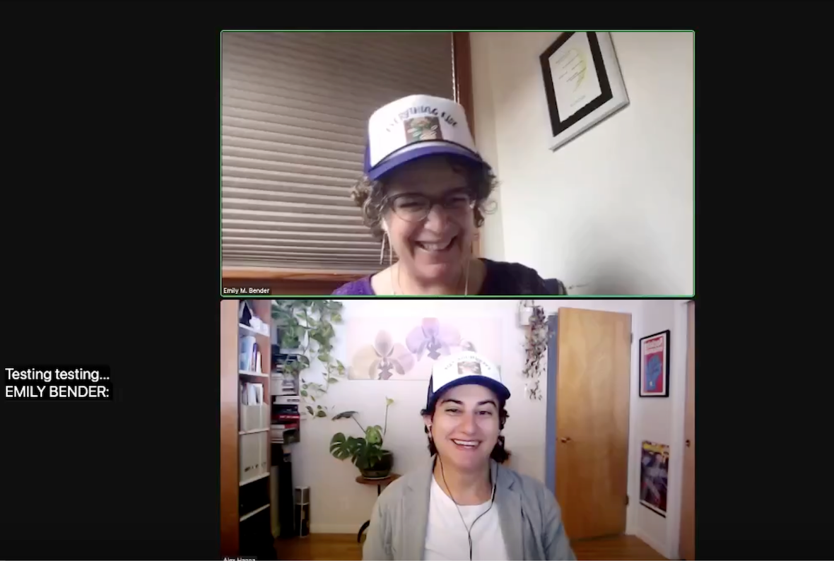Screenshot of a Zoom meeting. On the top is Emily Bender, a white woman with short-ish curly brown hair. She wears glasses and a purple top, as well as a white baseball cap with a blue brim. Behind her is a white wall and some closed beige window blinds. On the bottom panel is Alex Hanna, an Arab woman with medium-length black hair. She is also wearing a white baseball cap with a blue brim, and she also wears a white shirt and gray cardigan. Behind her is a room with bookshelves on one side and several plants.