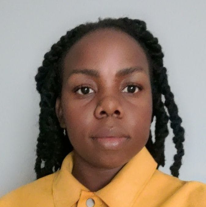 Raesetje Sefala, a Black woman, wearing a yellow shirt, with her hair in locks. 